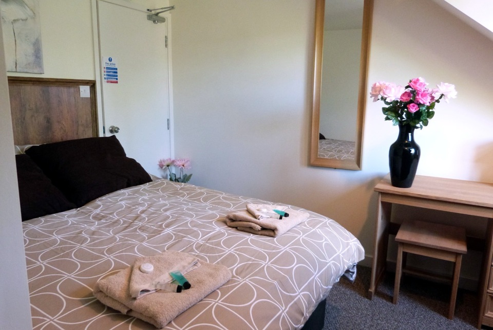 Double room with a grey patterned duvet and dark cushions