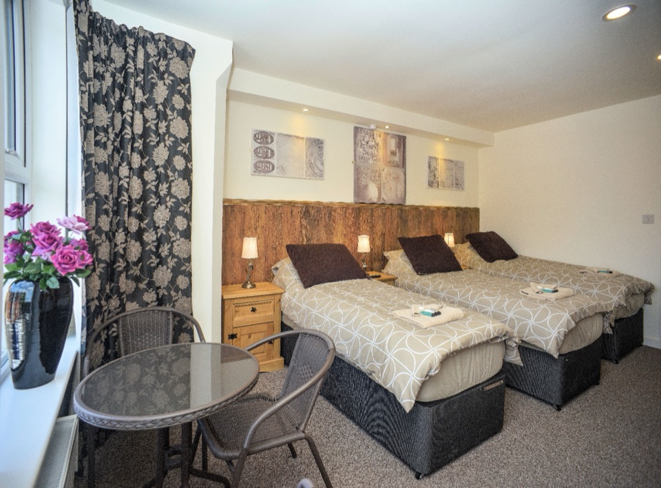 Triple room with three single beds and a small table with chairs