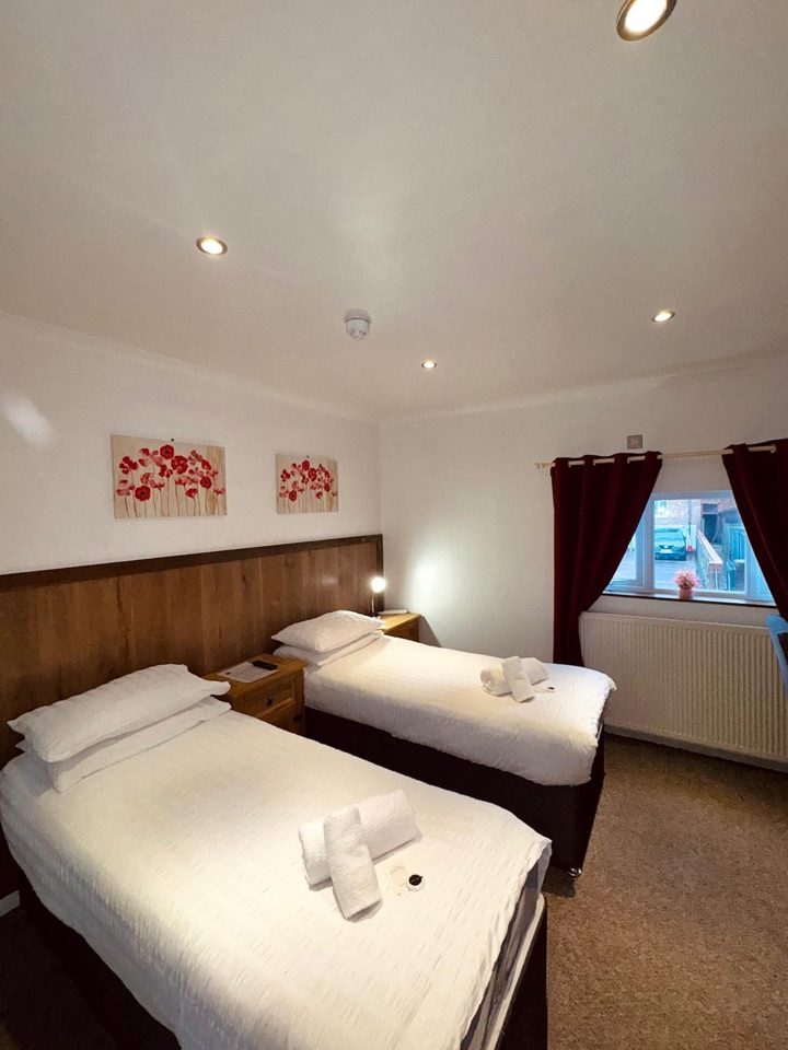 Twin room with two single beds, red poppy canvases and a window with red curtains